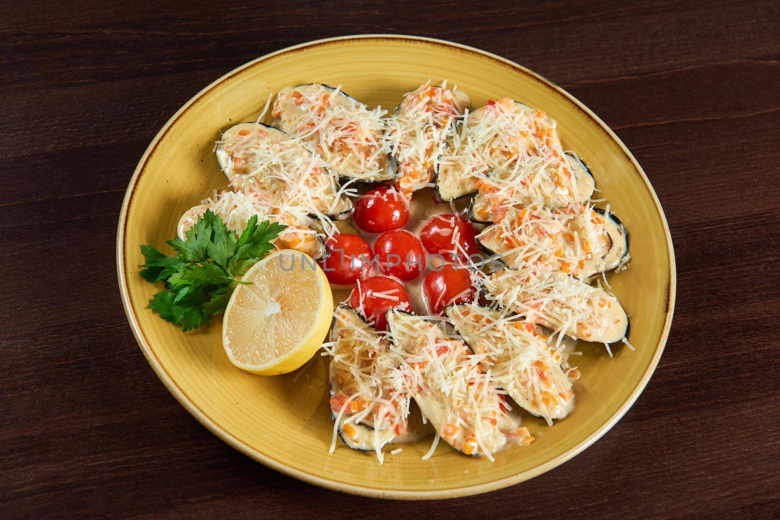 Seafood. Top view of shellfish mussels baked with cheese served with cherry tomatoes and lemon