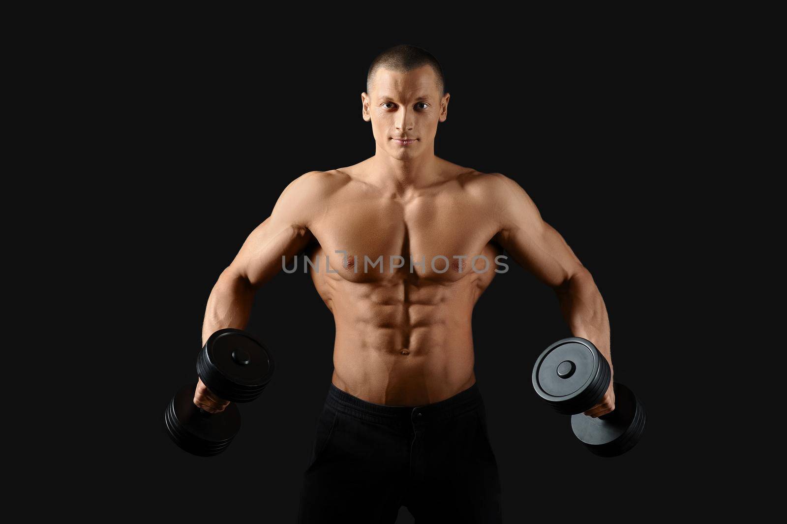 Broadening his back. Studio shot of an attractive young shirtless man pumping iron showing off his ripped abs