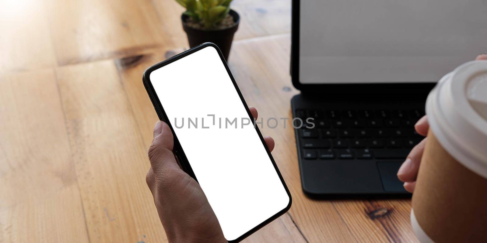 Mockup image blank white screen cell phone.women hand holding texting using mobile on desk at home office. by wichayada