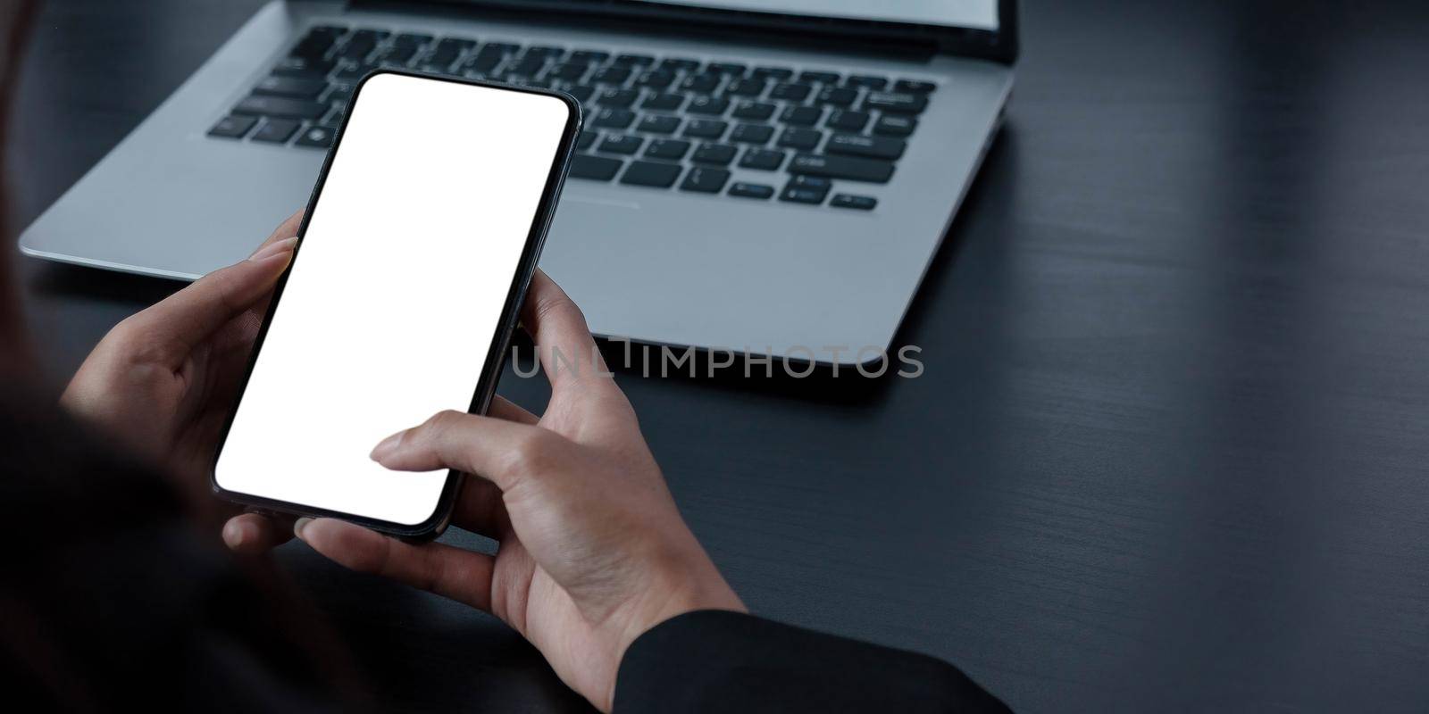 Mockup image blank white screen cell phone.women hand holding texting using mobile on desk at home office..