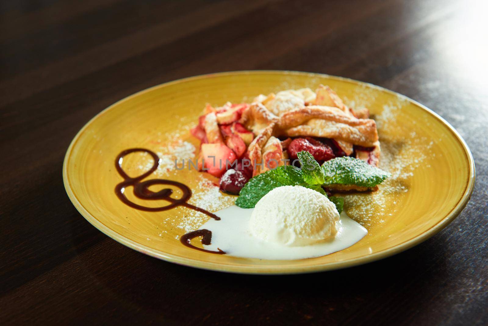 Pastry art. Closeup of a scoop of ice cream on a plate with a piece of fruit strudel