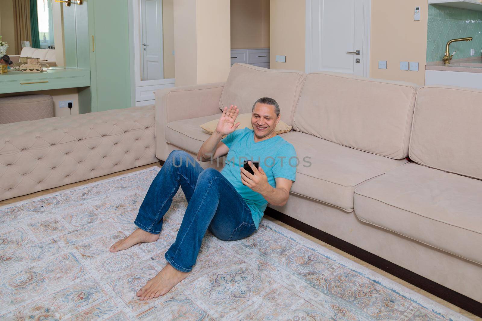 An adult man on the phone talking on video in an apartment.