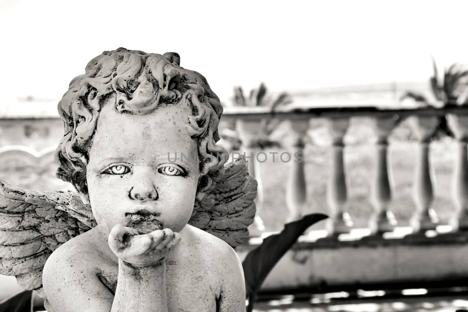 Elche, Alicante, Spain- July 3,2021: Beautiful angel sending a kiss made of white stone in a garden in Spain