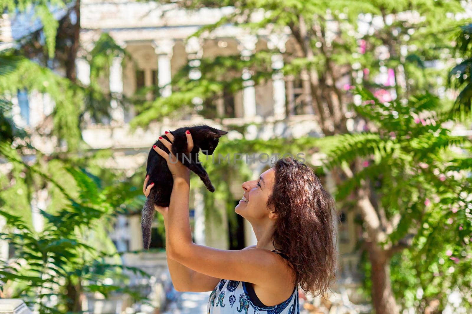 A young girl plays with a black kitten she found on the street.