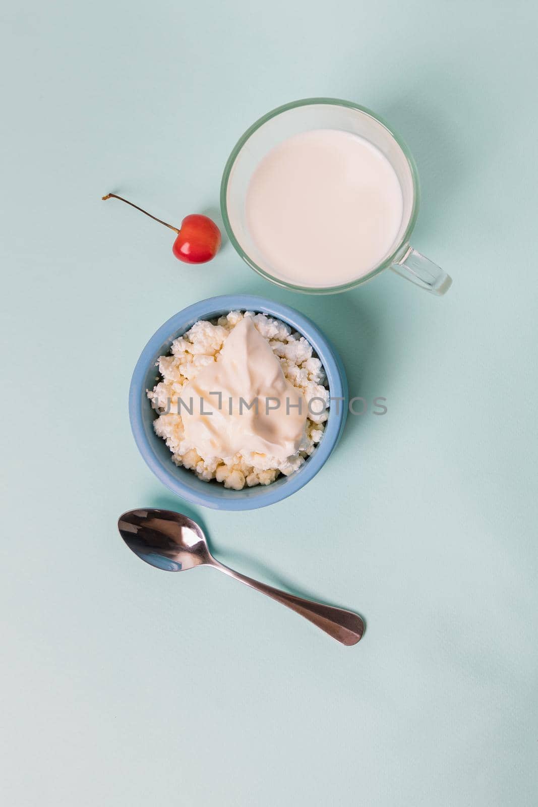 Cottage cheese in a blue bowl with sour cream and honey, a cup with milk. Morning breakfast.