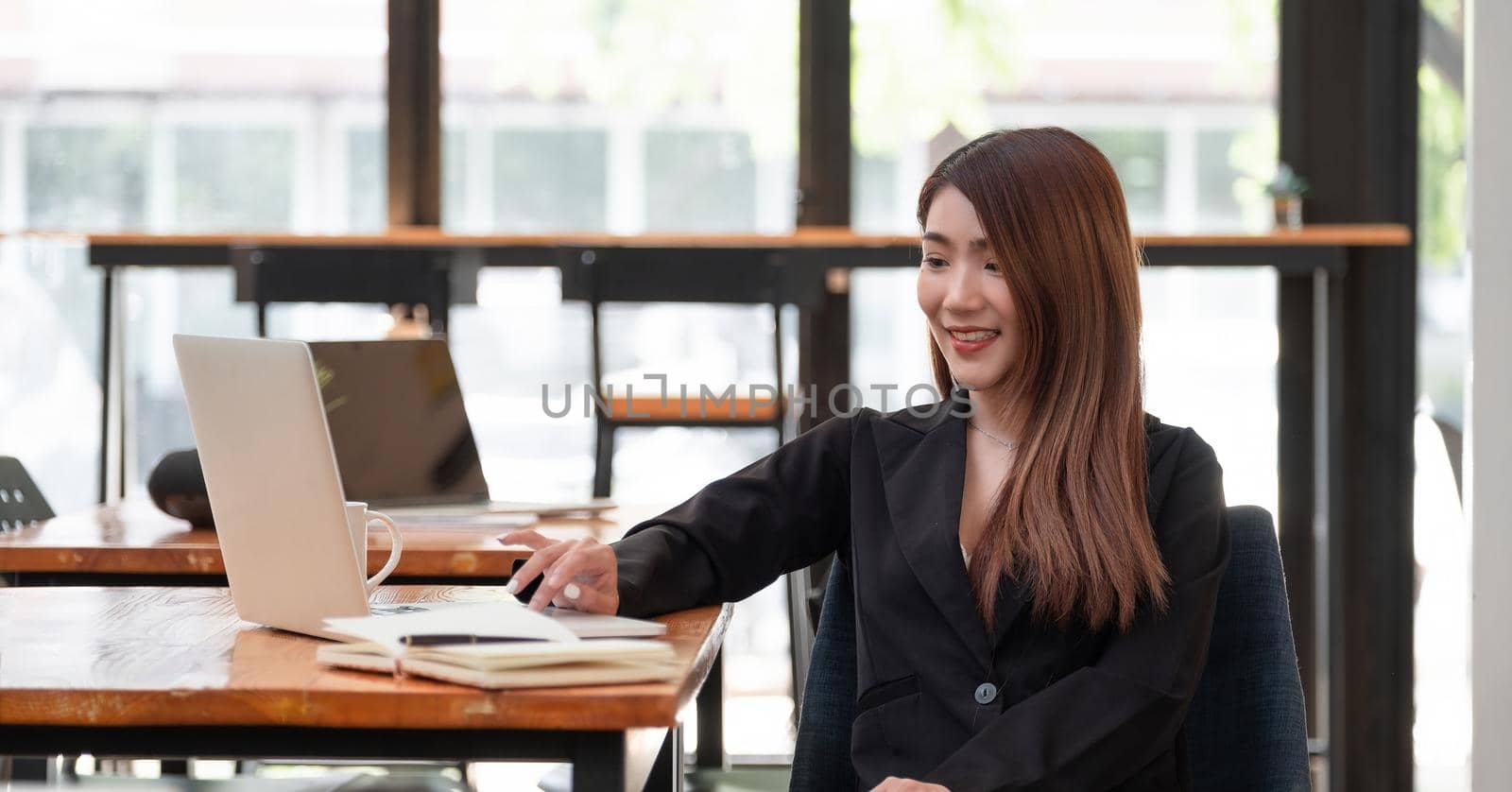 Shot of beautiful young asian woman working on laptop while sitting at coffee shop