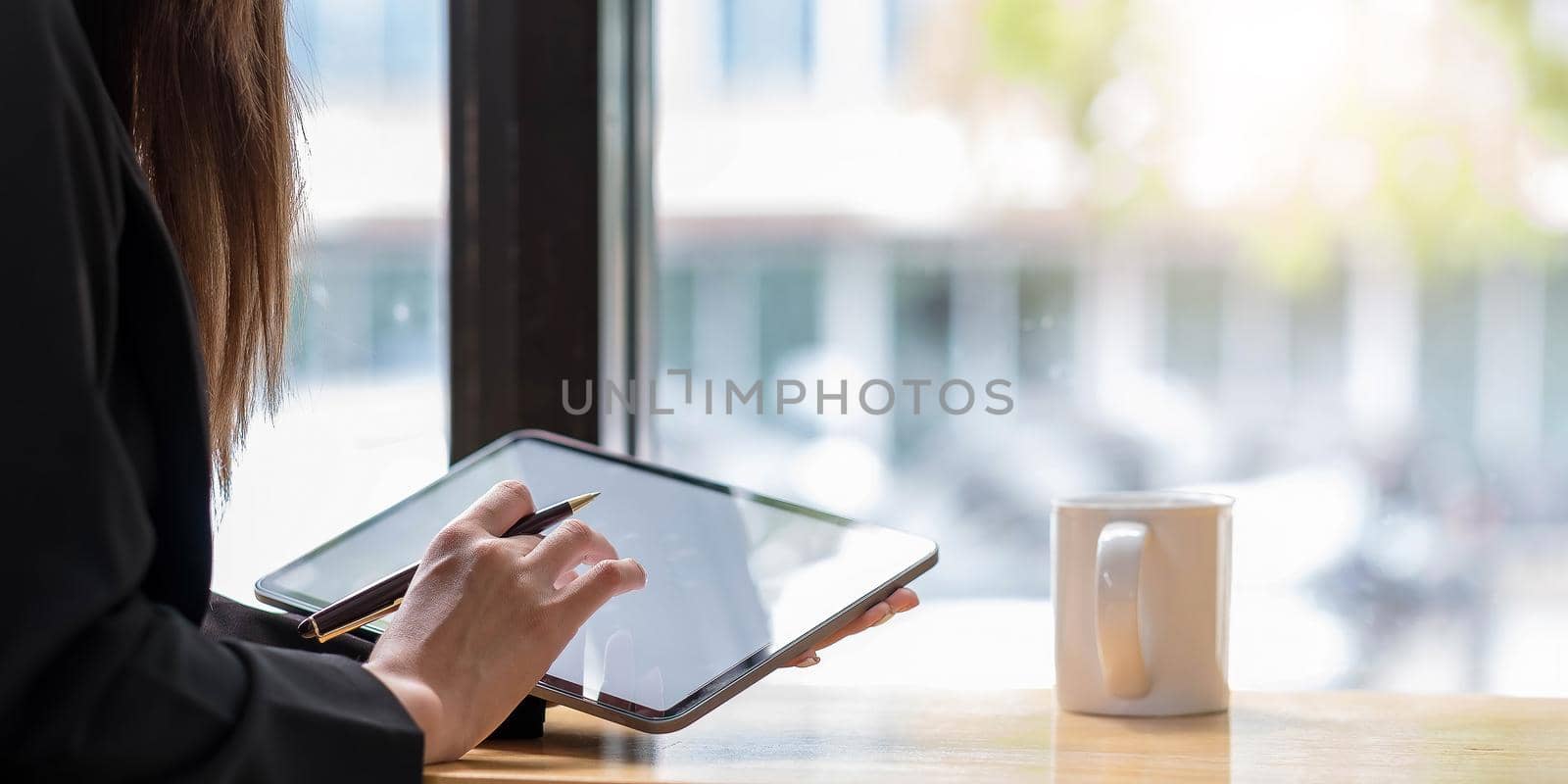 Above view of woman holding digital tablet and stylus pen on her office desk. by wichayada