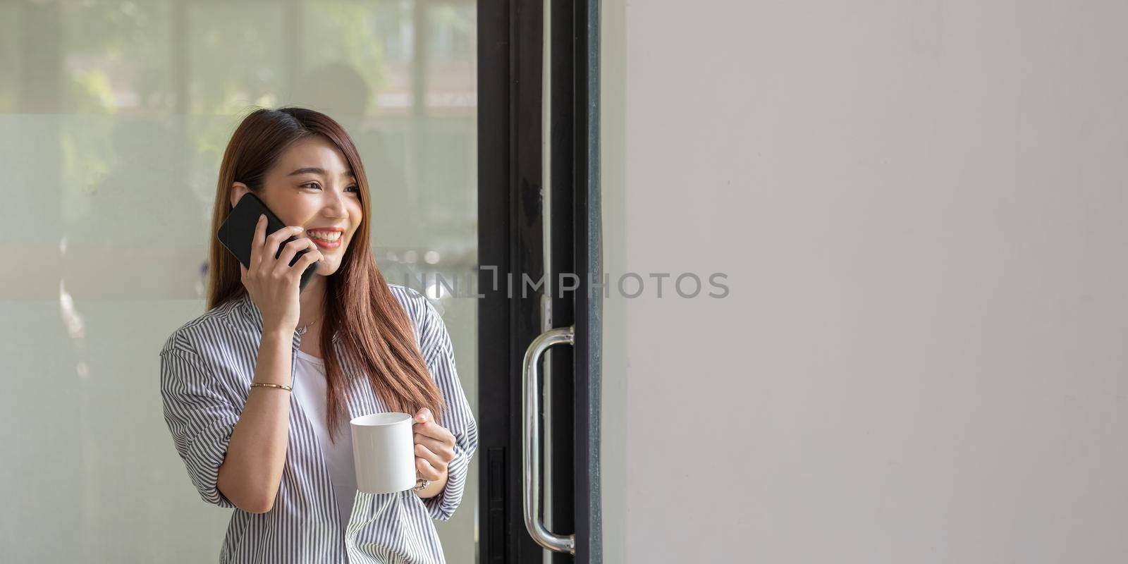 Smiling asian woman talking on the phone at home, happy young girl holds cellphone making answering call, attractive teenager having pleasant conversation chatting by mobile with friend. by nateemee