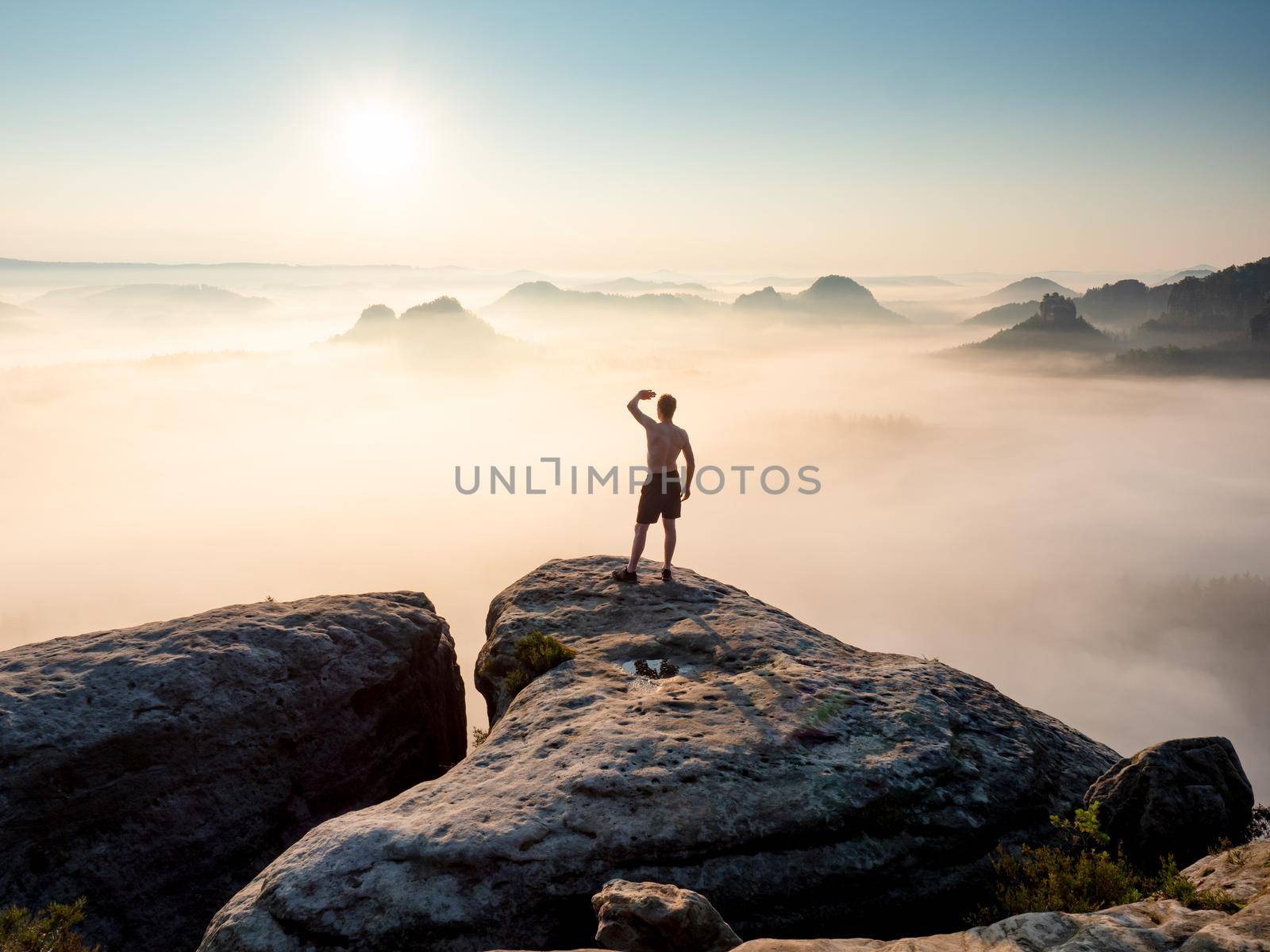 Silhouette of shirtless tourist and a beautiful misty hilly landscape as a backdrop