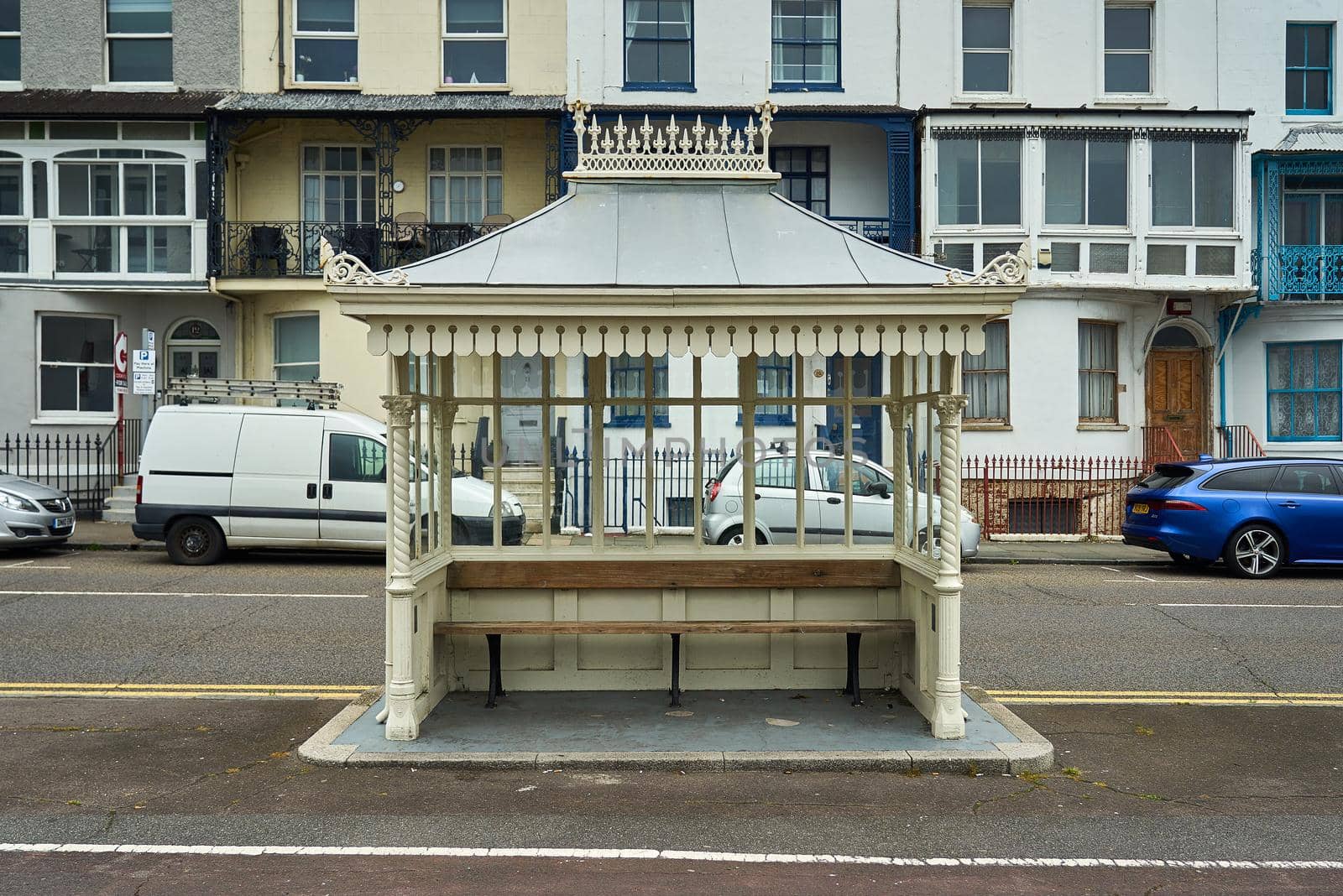 The shelter has a bench and glass to protect people from the weather