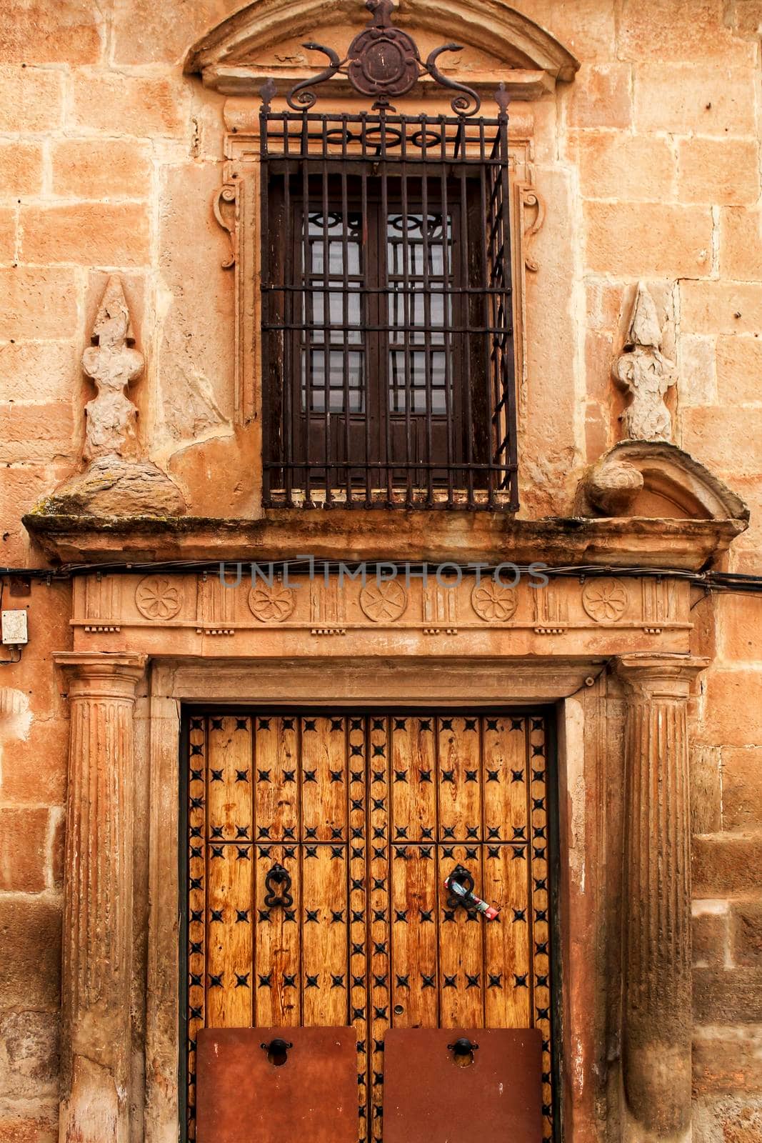 Old stone facade made of carved stone and vintage wooden door in a majestic house in Villanueva de los Infantes, Ciudad Real community, Spain