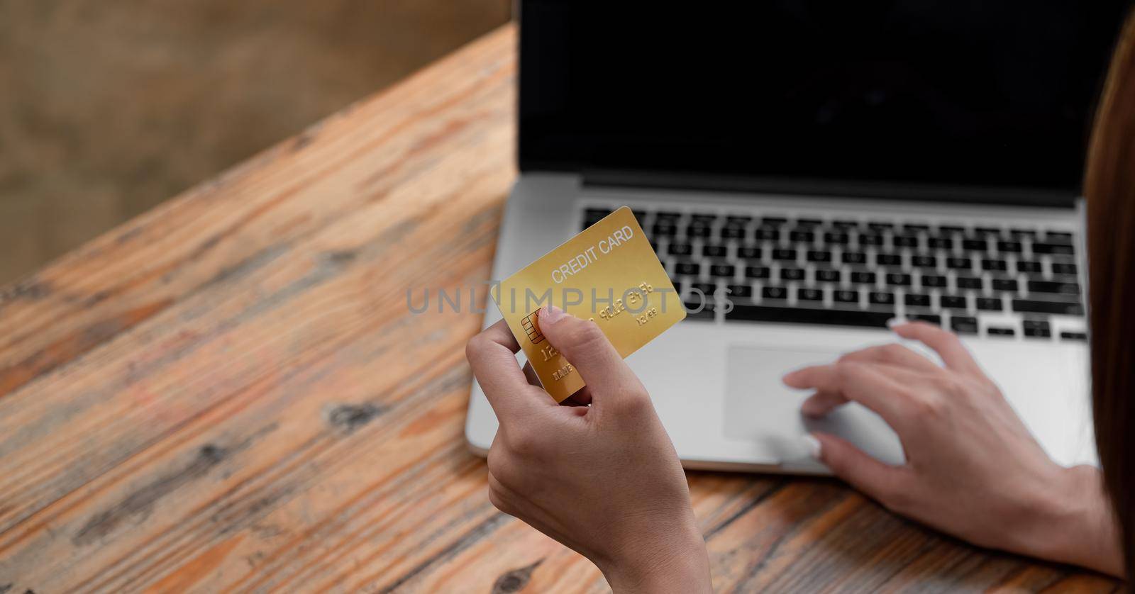 Hands holding credit card and using laptop. Online shopping at coffee shop cafe.