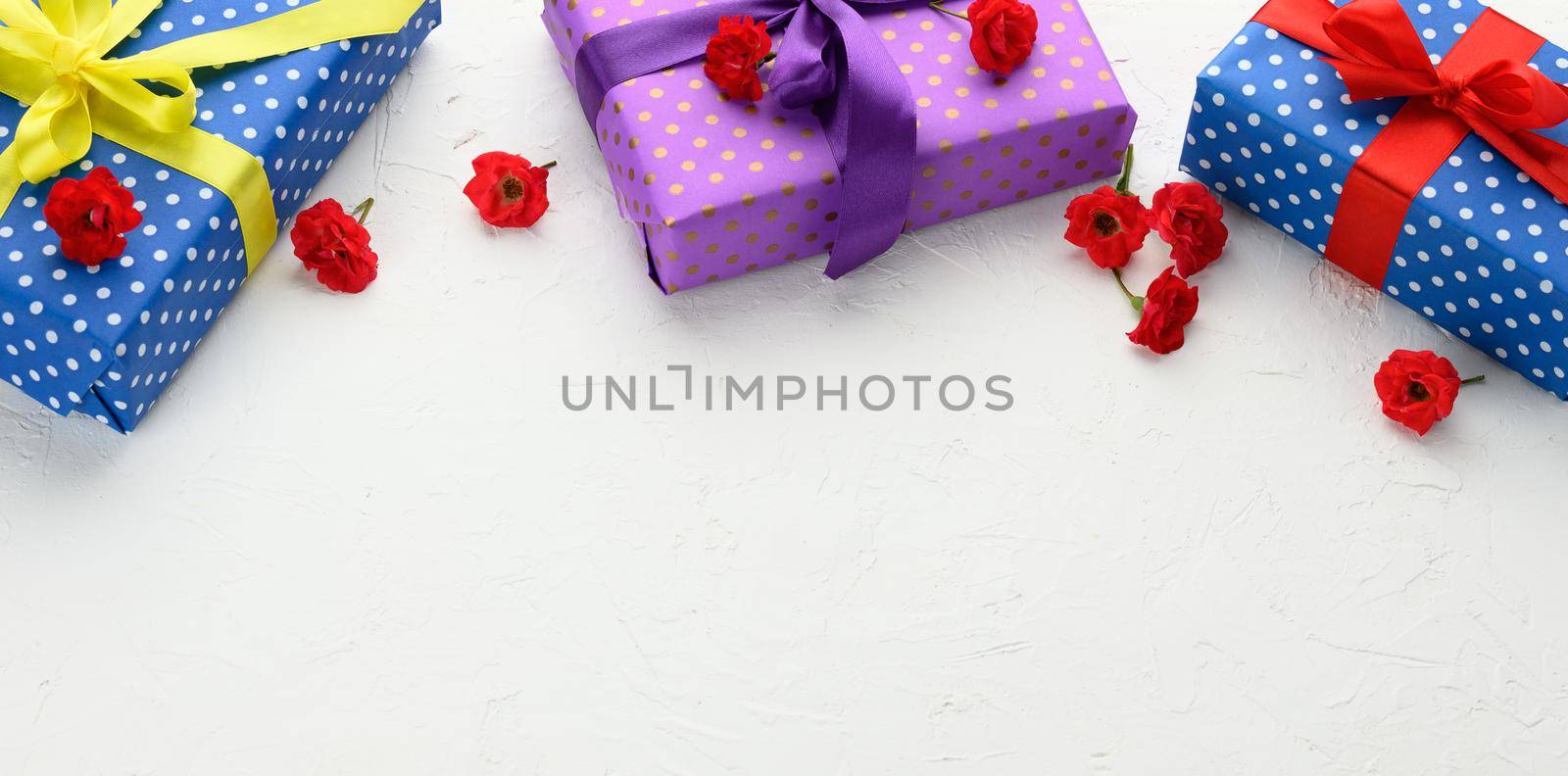 boxes are packed in holiday paper with polka dots and tied with a silk ribbon on a background, birthday gift, surprise by ndanko