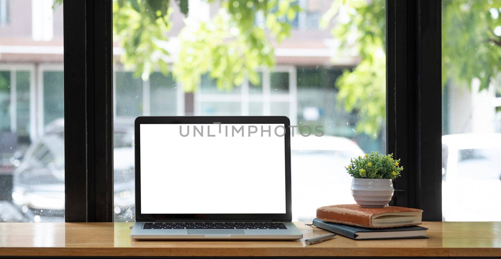 Laptop with blank screen on table of coffee cafe shop.