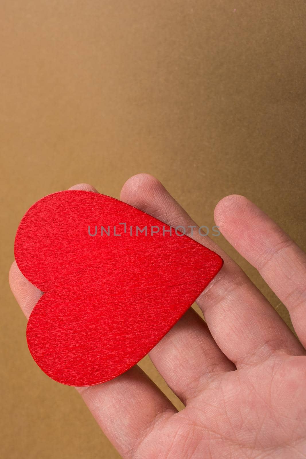 Red color heart shaped object in hand  on dotted paper