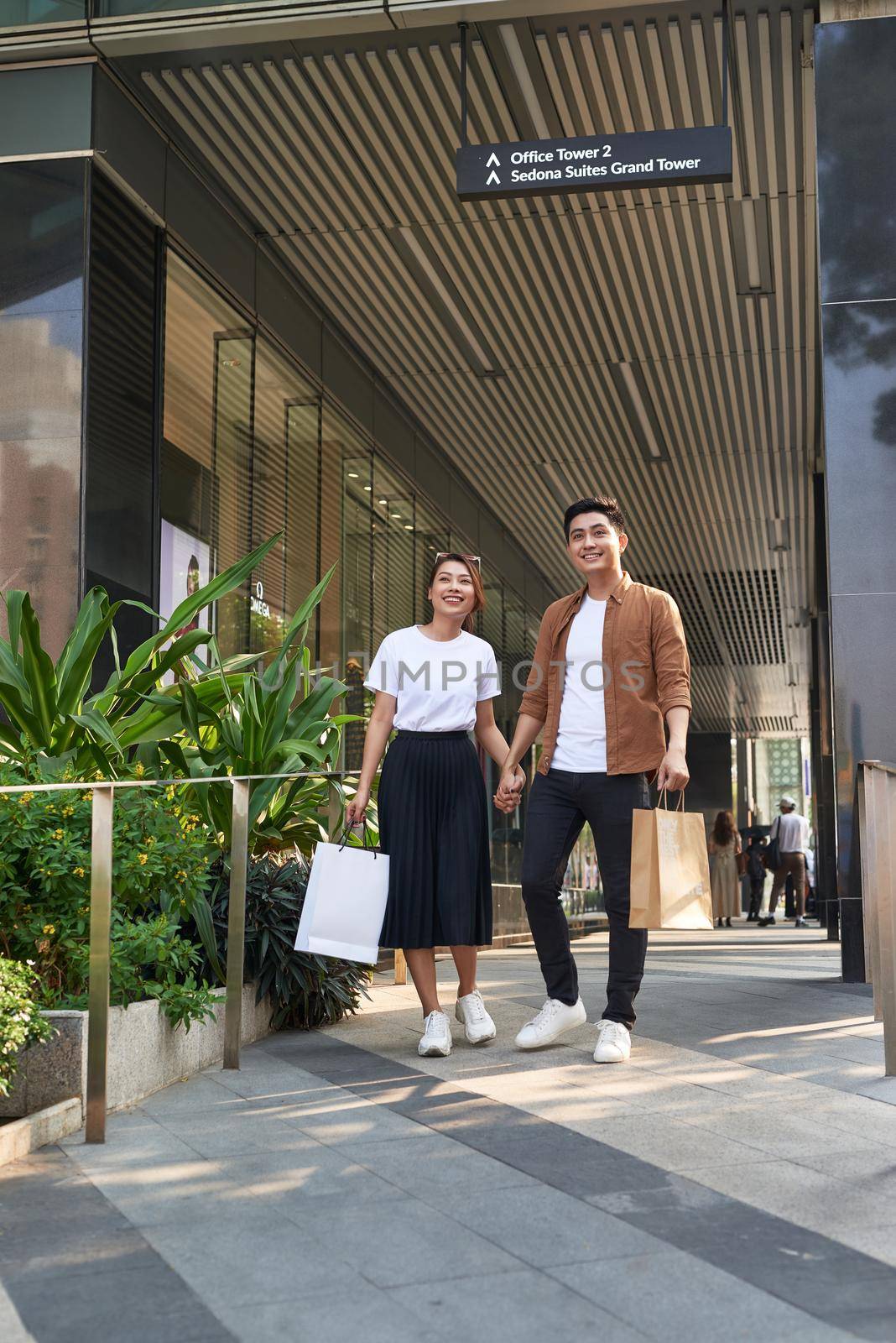 Beautiful young loving couple carrying shopping bags and enjoying together.  by makidotvn