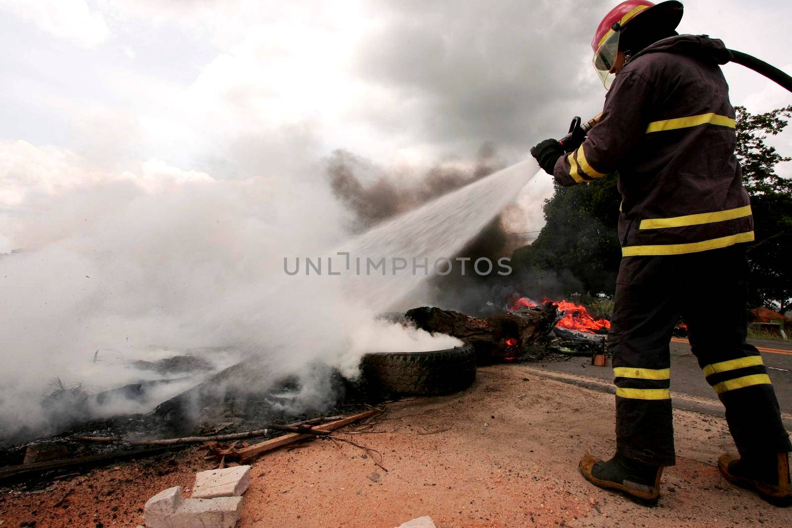porto seguro, bahia, brazil - march 2, 2010: member of the Fire Department puts out a fire on the BR 367 highway caused by protesters during a protest in the city of Porto Seguro.