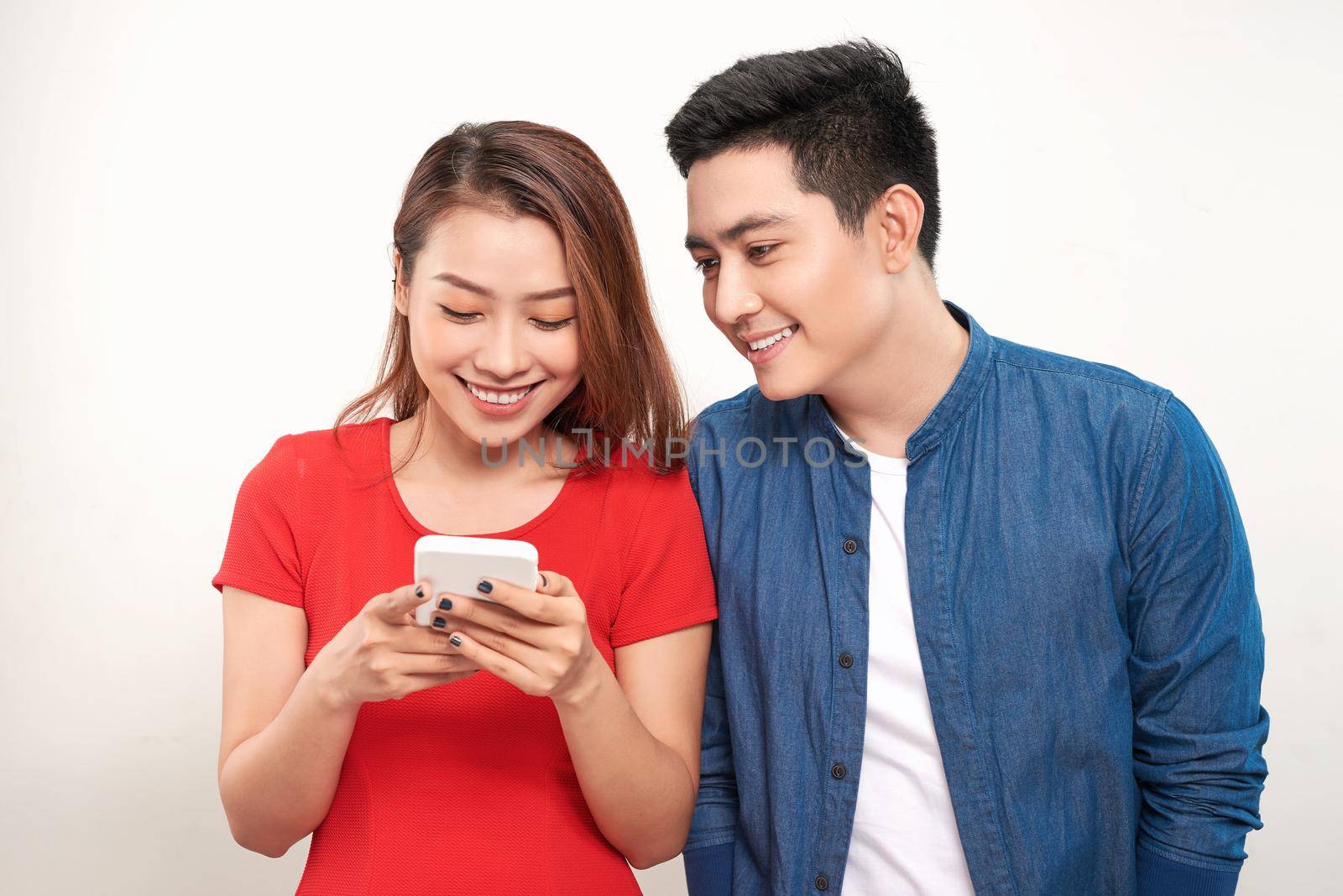 Asian couple using cell smart phone message smile standing on white background