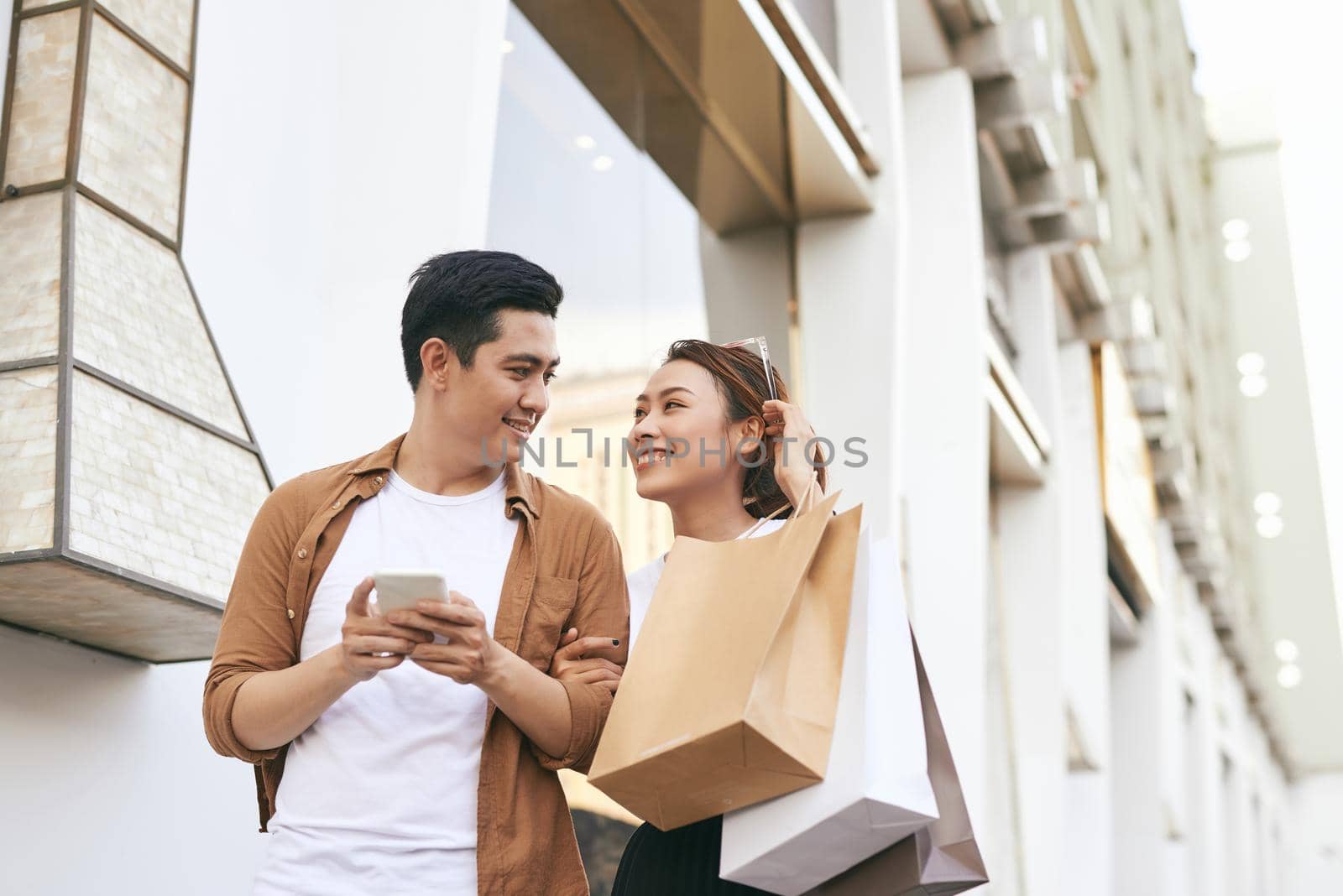 Happy beautiful couple using smart phone and shopping together.