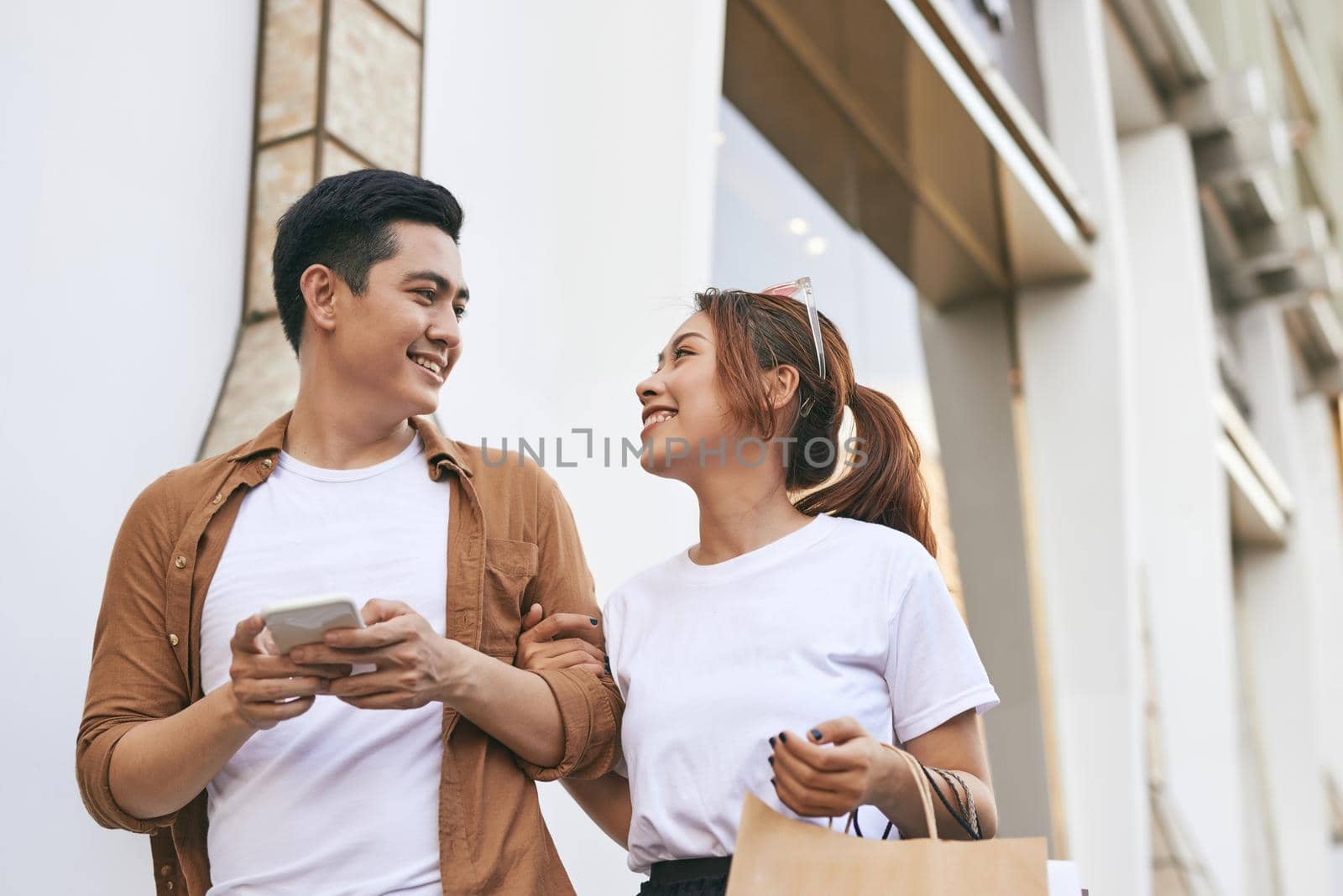 Happy beautiful couple using smart phone and shopping together.