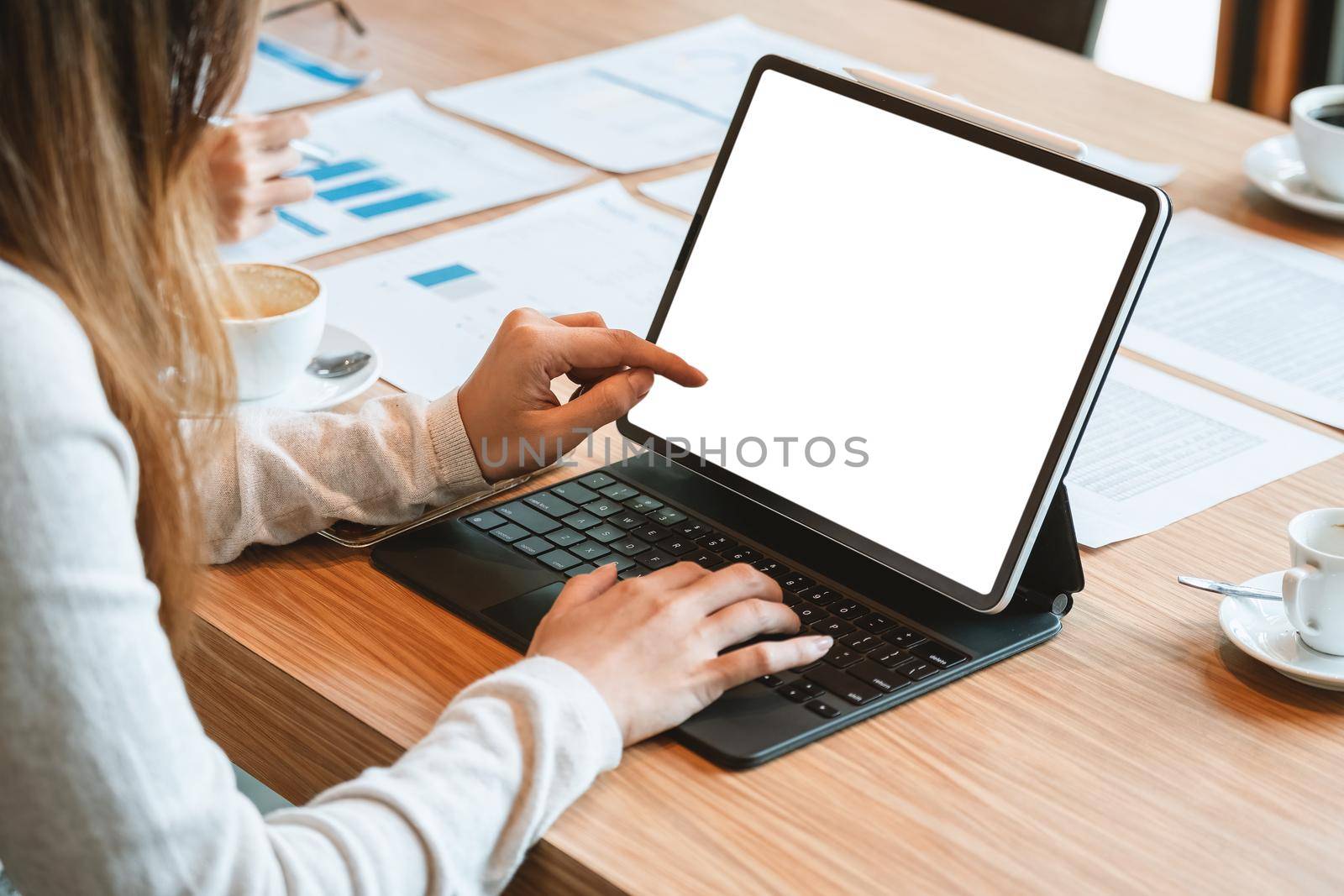 Cropped image of woman holding digital tablet with mock up screen reading online book in coffee shop, female's finger tapping on portable computer checking feeds in social networks via wifi