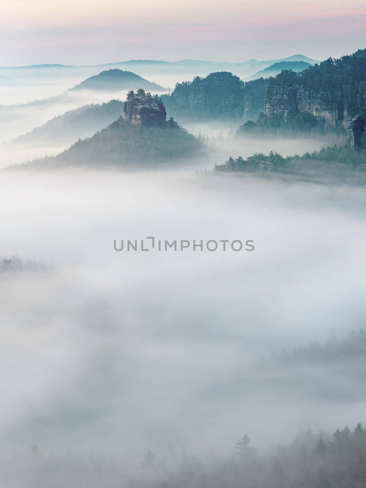 The fairy rock of Winterstein, also called Hinteres Raubschloss or Raubstein sticking out of morning mist.  It is a sandstone rock massif, the butte with rest of stronghold ruin in the Saxon Switzerland National Park.