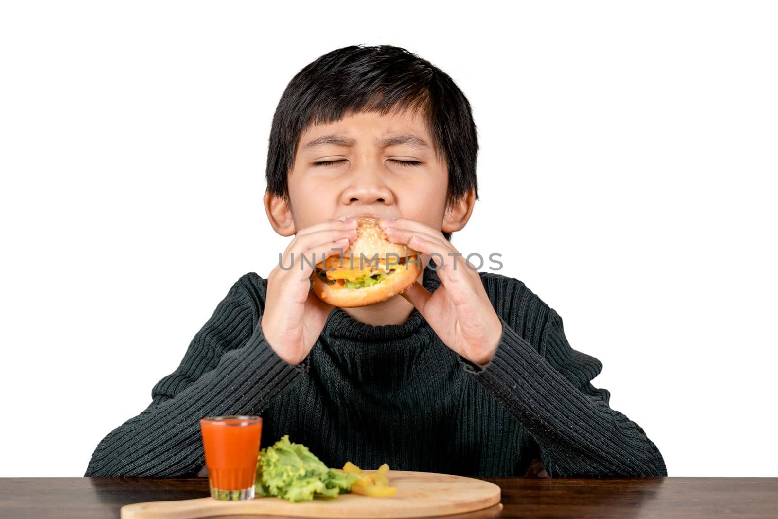 Cute Asian boy in black shirt eating a delicious hamburger on white background.