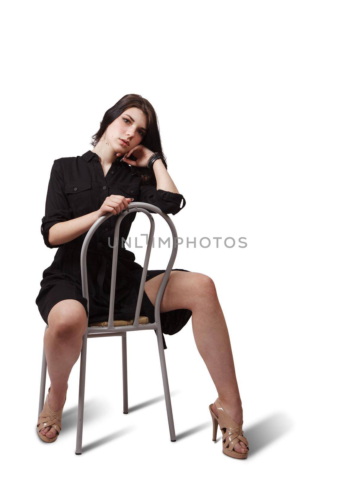 pretty girl in black dress posing in the studio sitting on a chair
