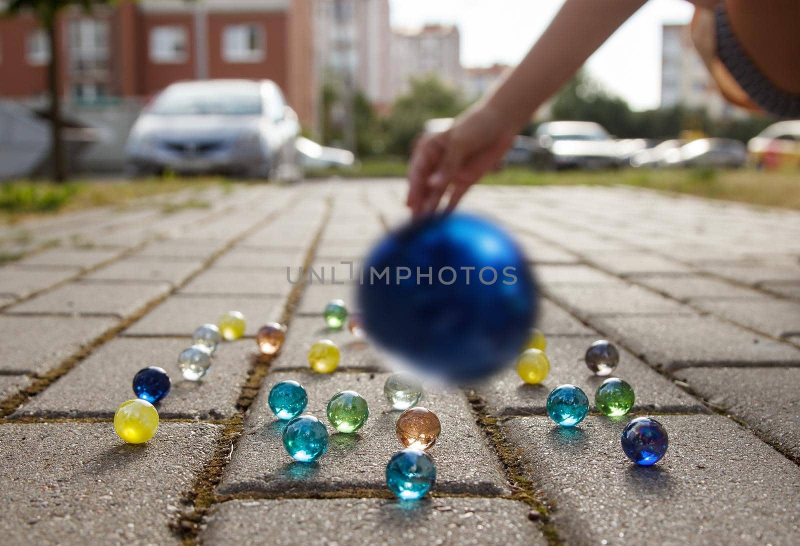 girl throws a glass ball on the sidewalk outdoor closeup