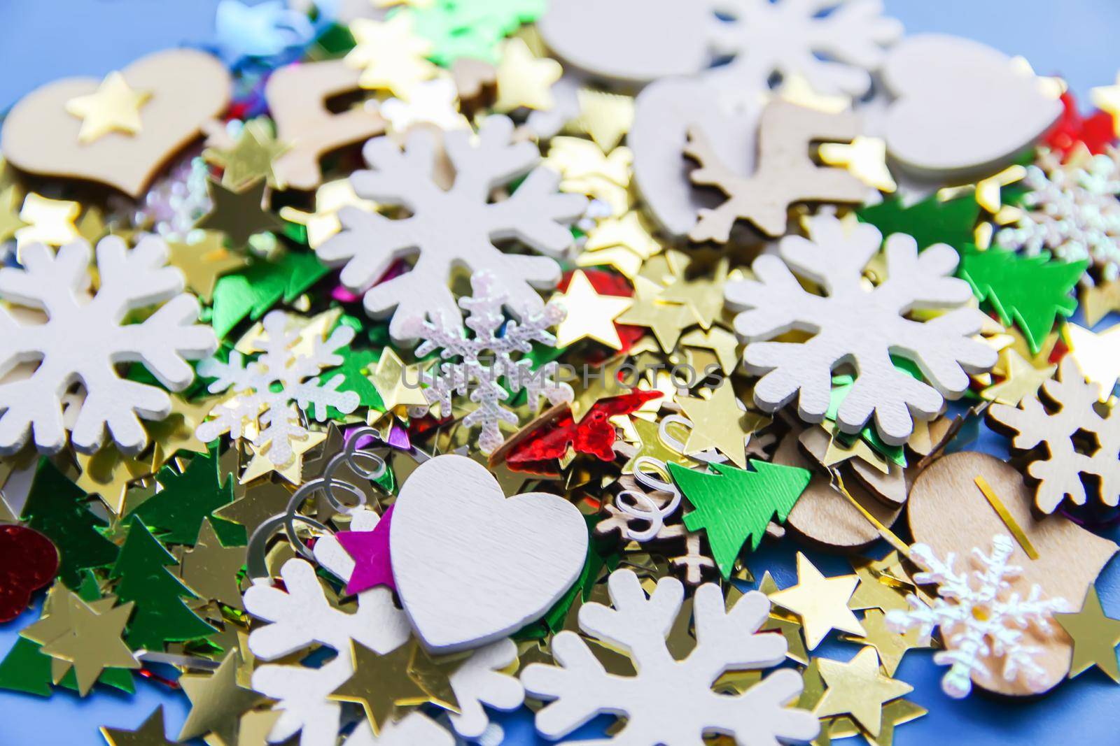 Christmas and New Year decorative background with small wooden snowflakes. Colorful tinsel. Festive confetti.