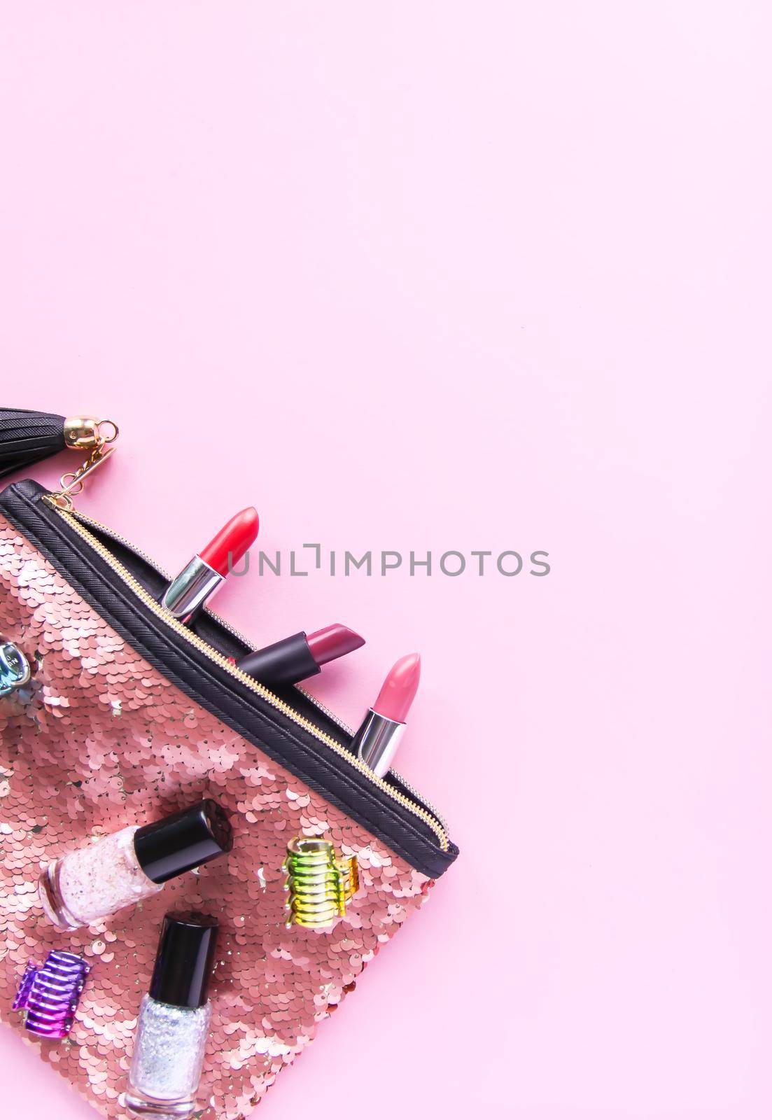 Bright composition of fashion accessories. Glitter sequins cosmetic bag with nail polishes, lipsticks, hair pins. Objects on soft pastel background. Flat lay, top view. by nightlyviolet