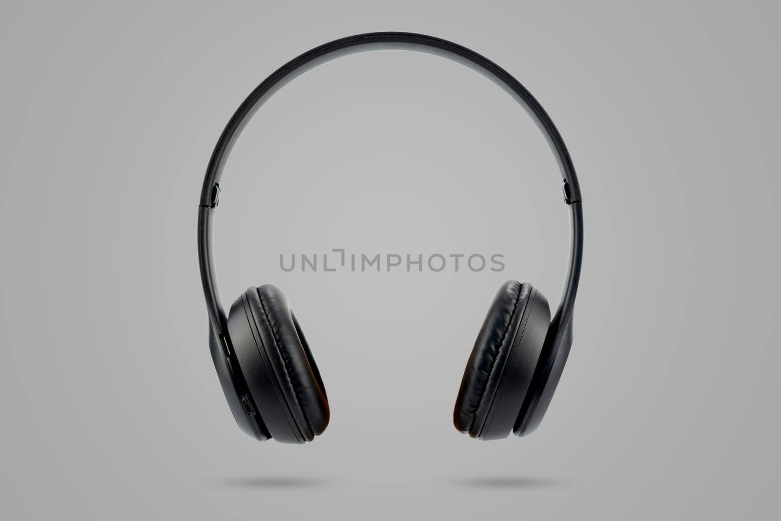 Modern design of black color wireless earphones isolated on gray color pastel background.