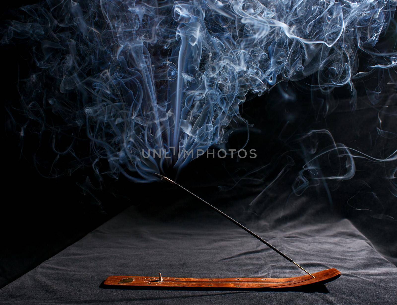 indian incense stick with smoke on black background indoor closeup