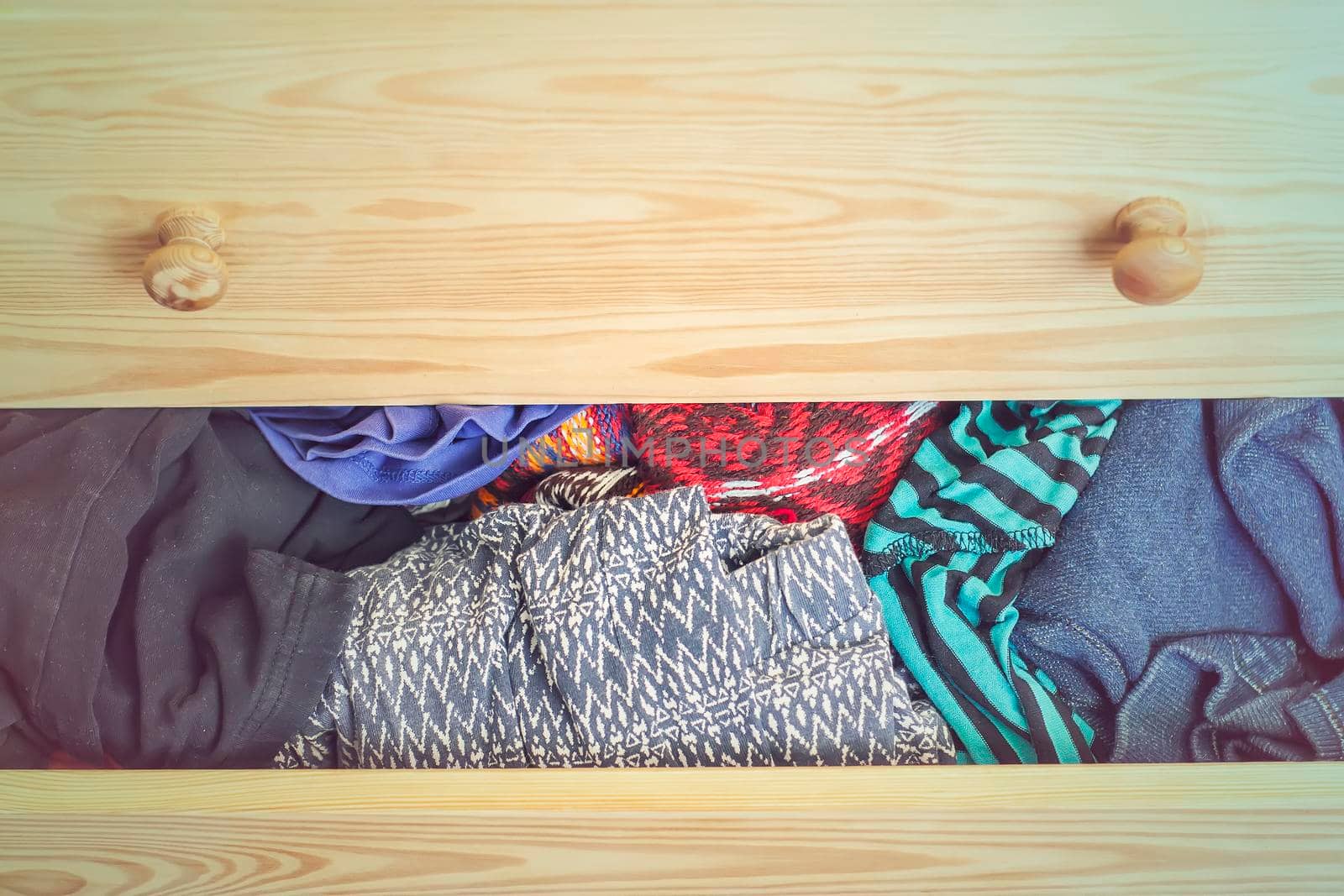 Open light wooden dresser drawer with colorful clothes. by nightlyviolet
