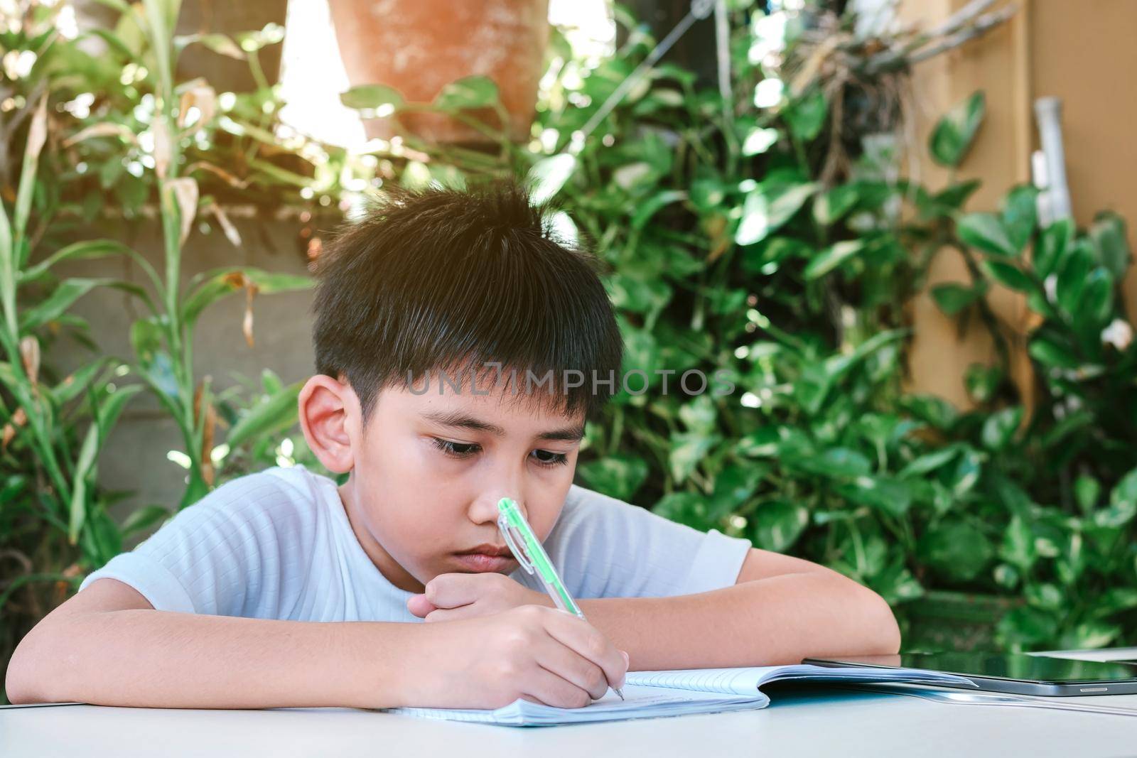 Asian boy doing his homework. by wattanaphob