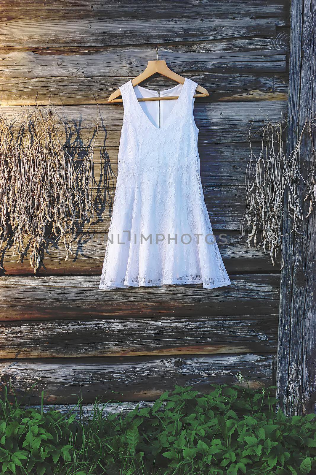 Linen dress hanging on a hanger outdoors on wooden rough wall background