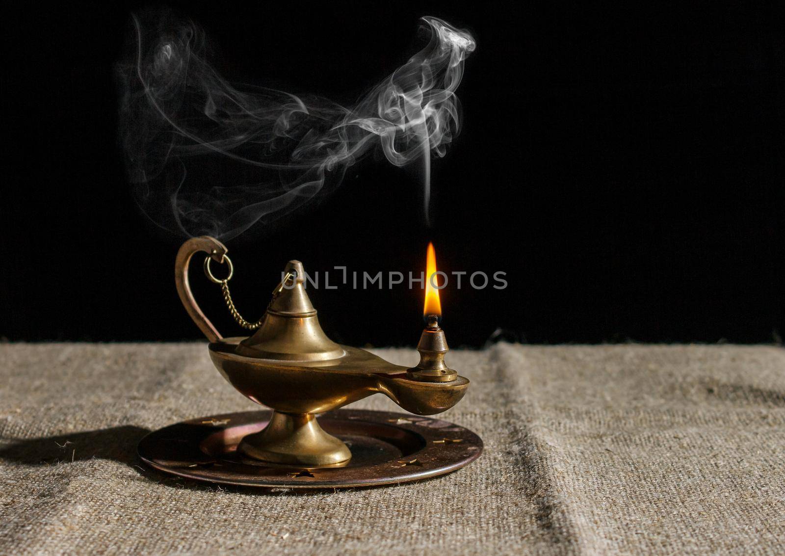 burning magic lamp of aladdin on table. indoor closeup on black background