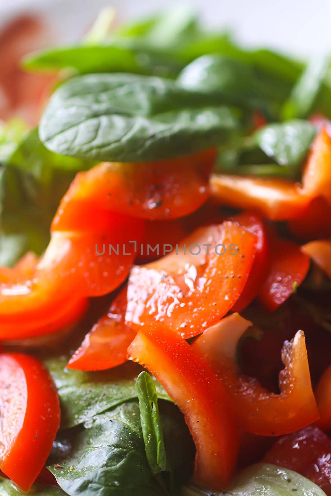 Fresh salad of the red tomatoes and spinach with olive oil, salt and pepper