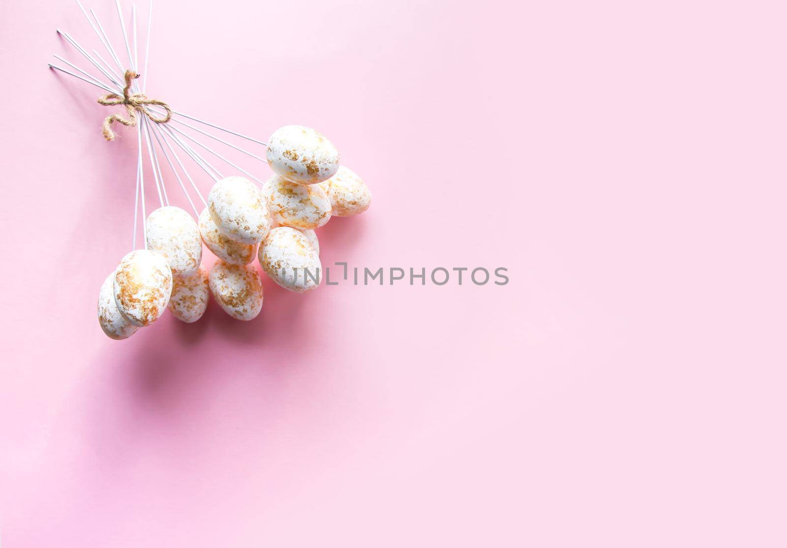 Easter composition with traditional decor of colorful eggs on sticks on soft pink pastel background