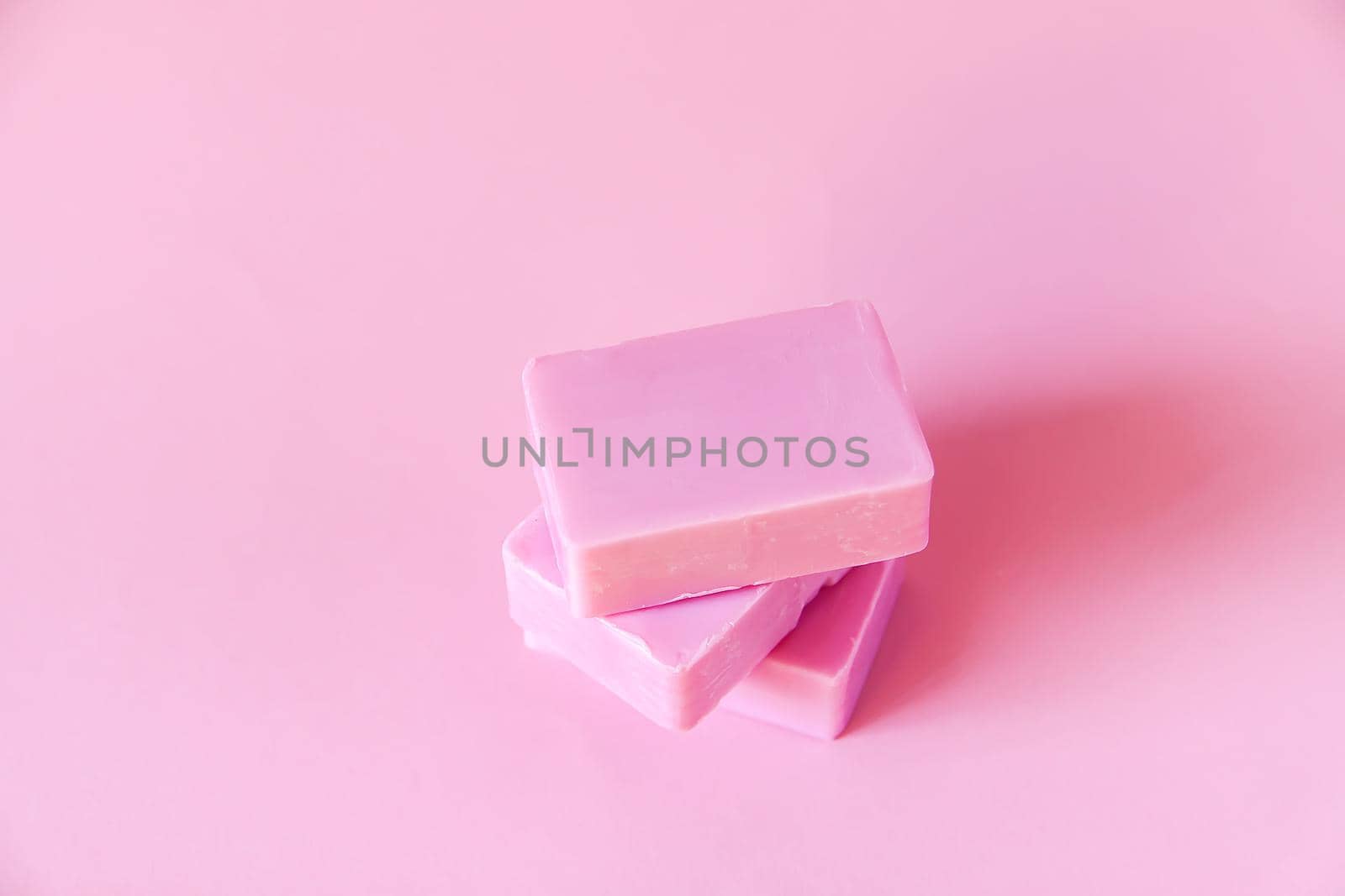 Handmade soap bars on soft pink background.