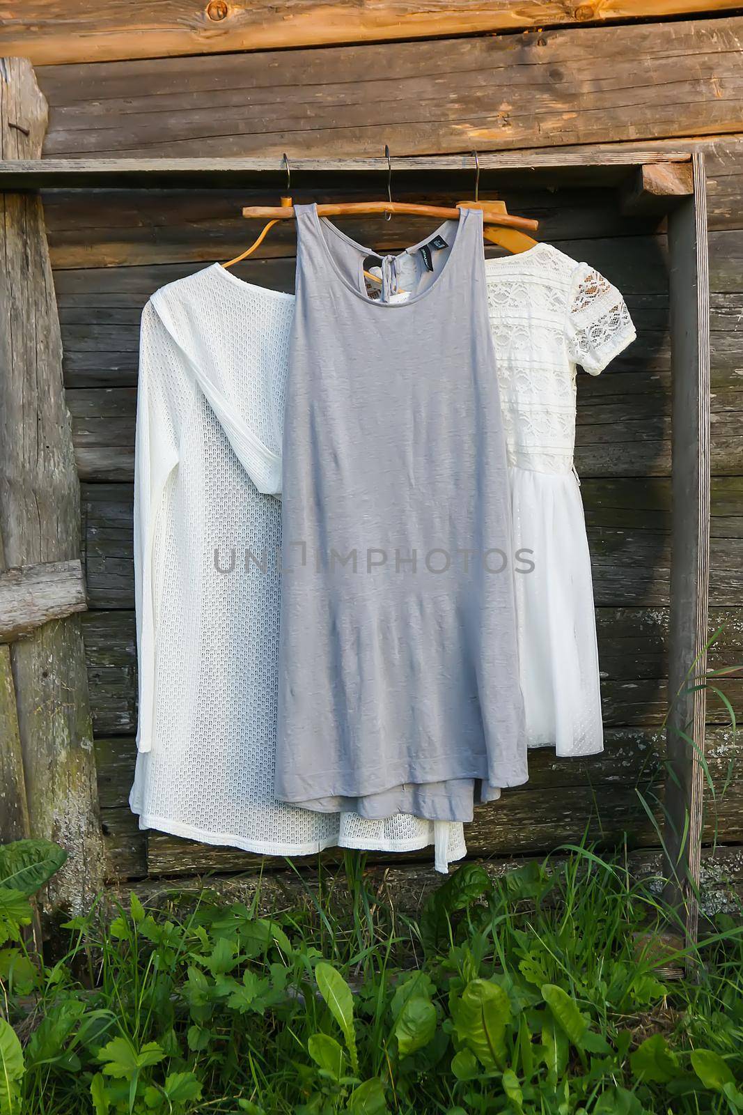 Linen dresses hanging on a wooden hangers outdoors in summer day