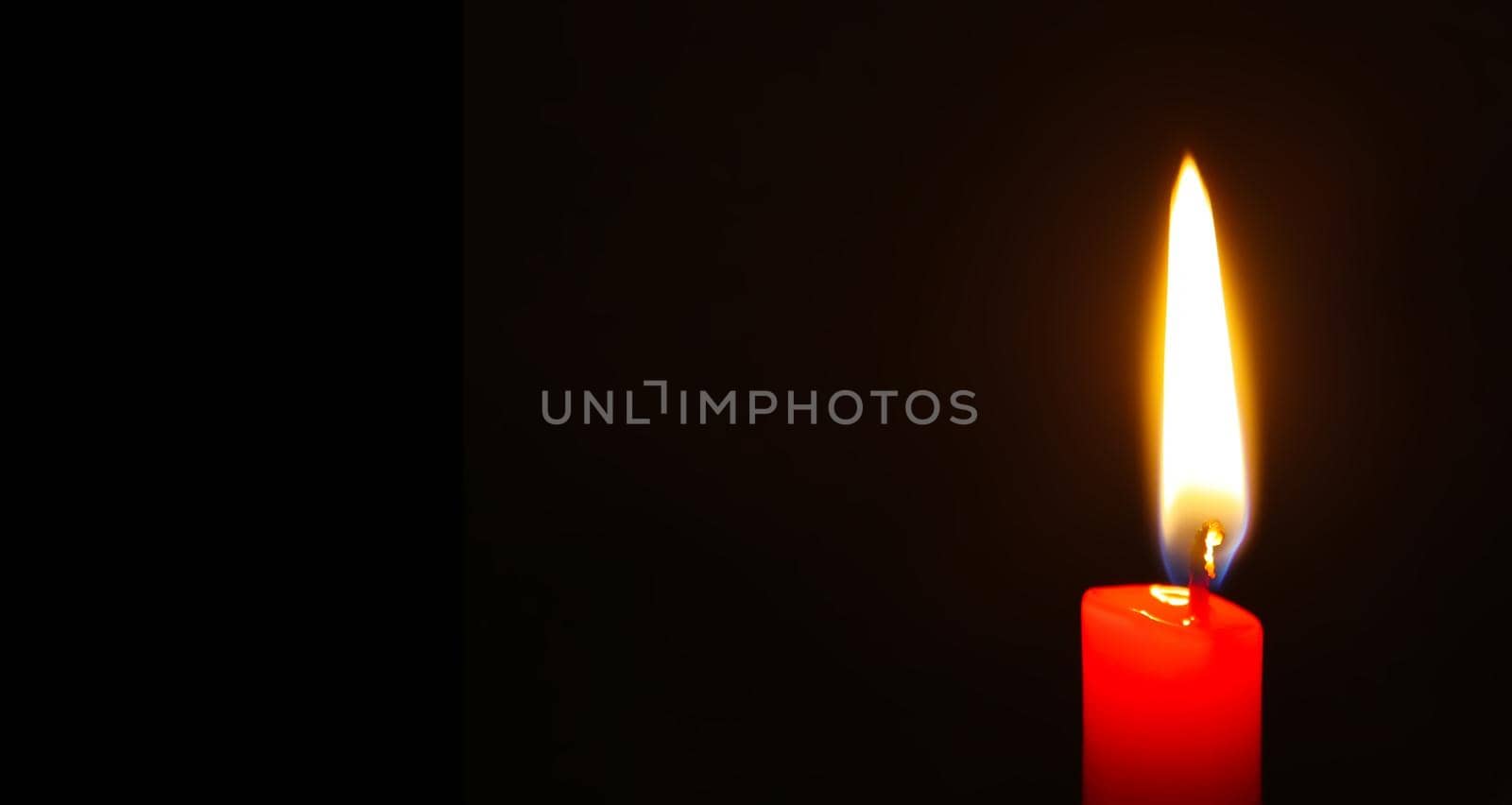 Red candle burning on black background. Long banner with copy space.