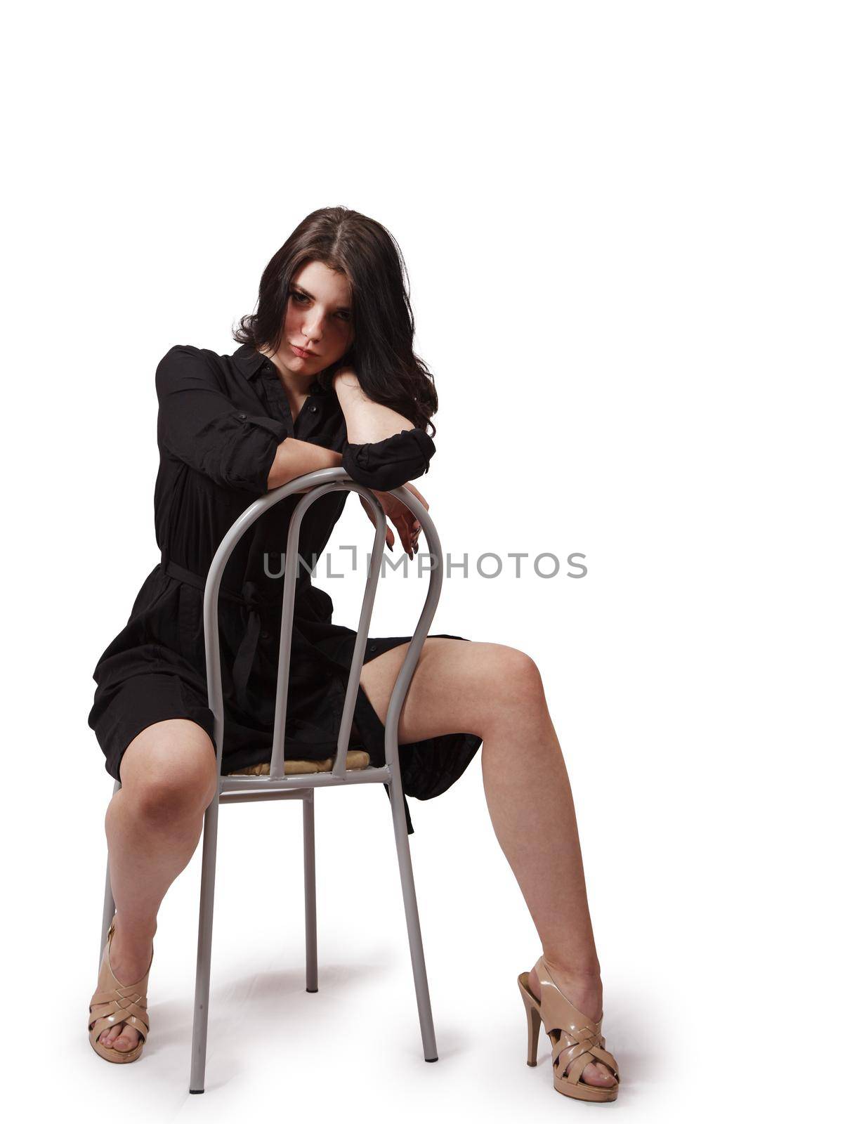 pretty girl in black dress posing in the studio sitting on a chair