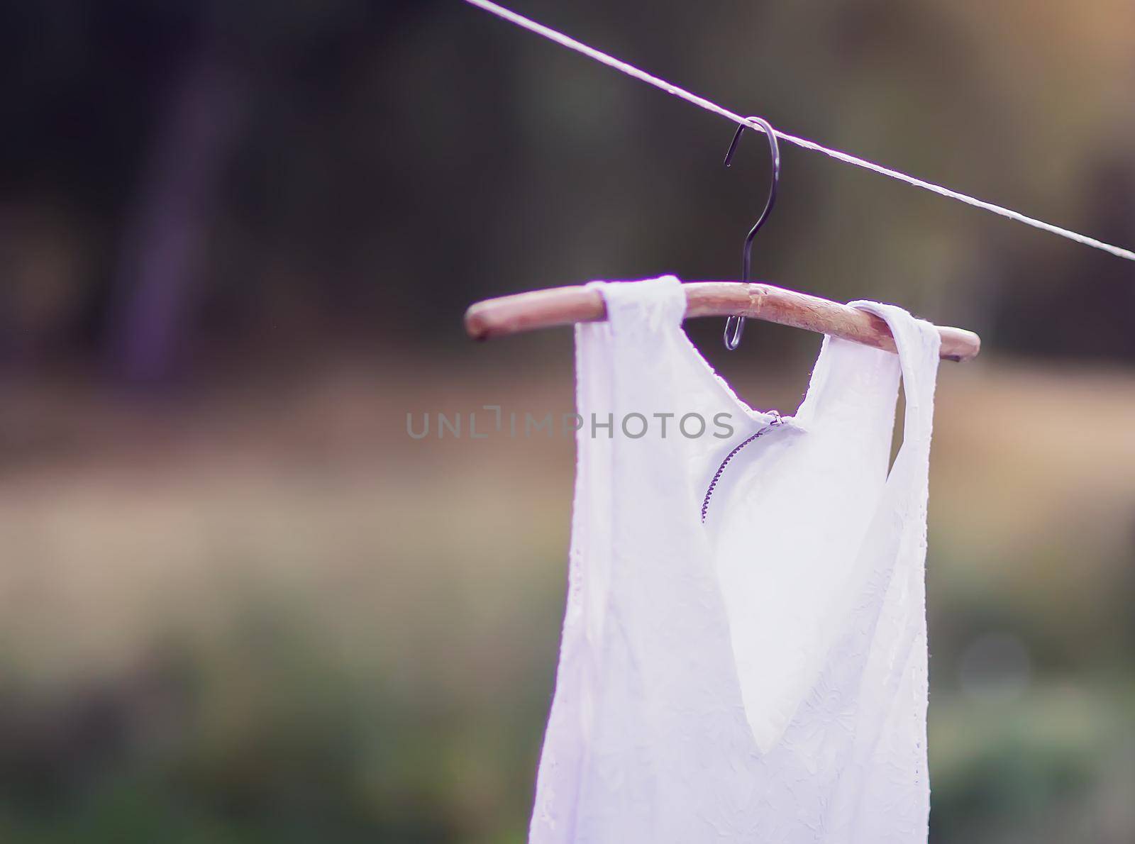 Linen dress hanging on a hanger outdoors in summer day
