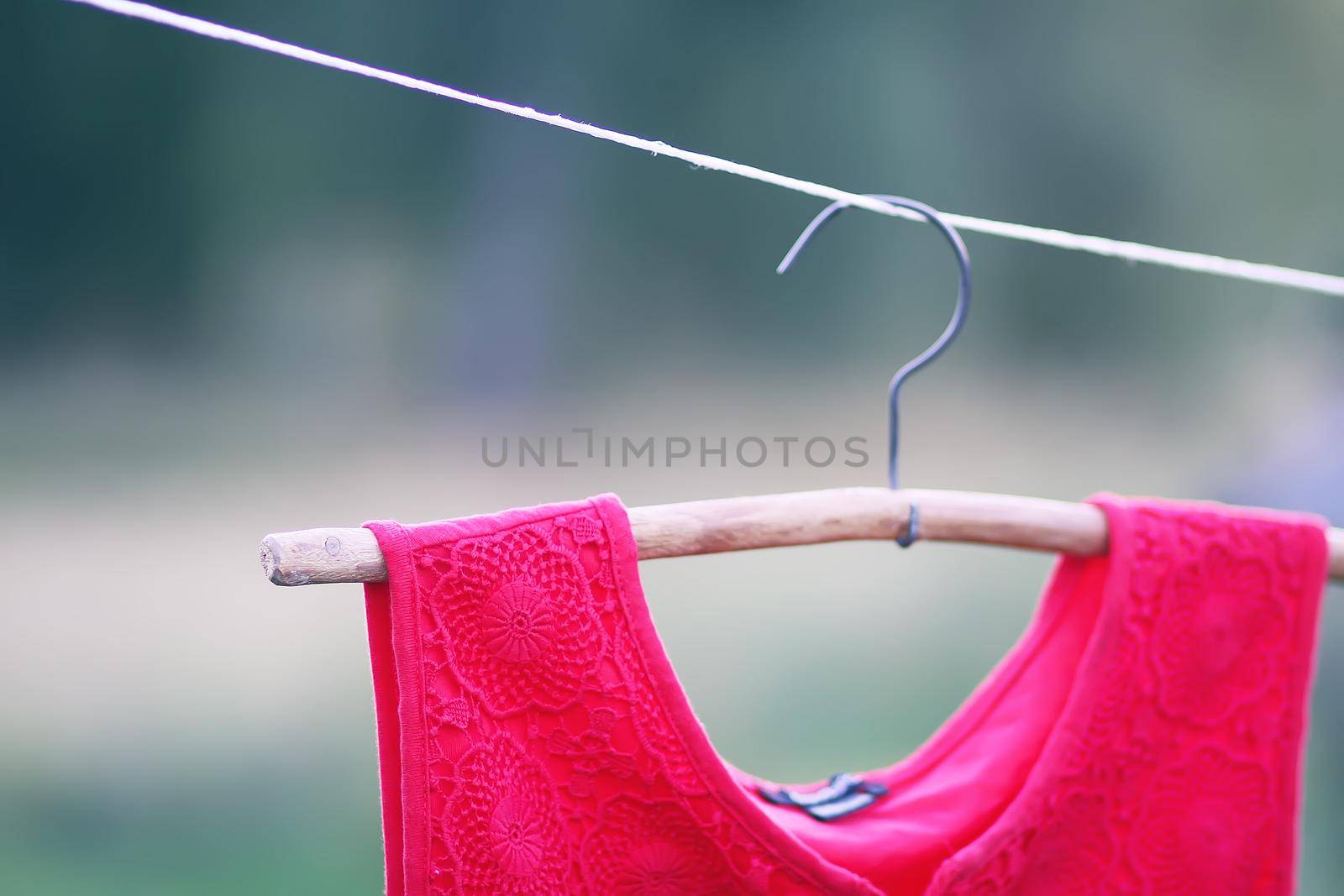 Linen red dress hanging on a hanger outdoors in summer day