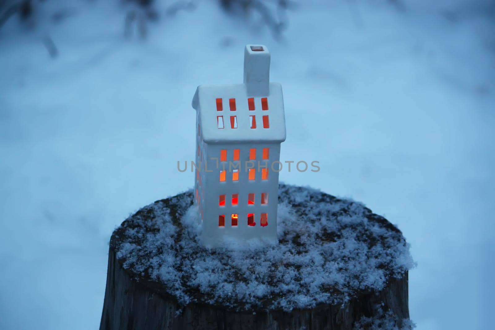 Christmas lantern with burning candle on winter nature background.