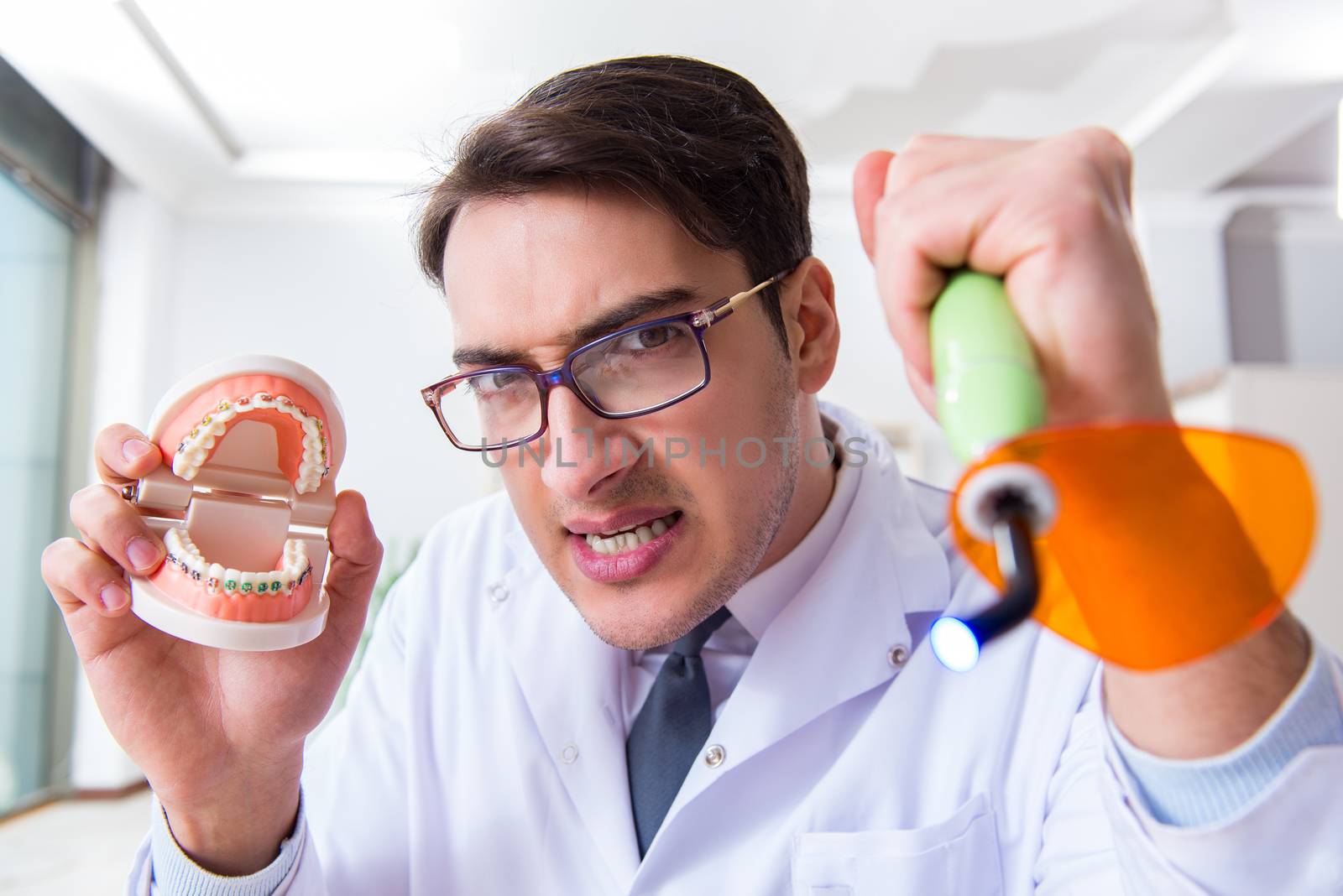 Funny dentist with curing light in medical concept