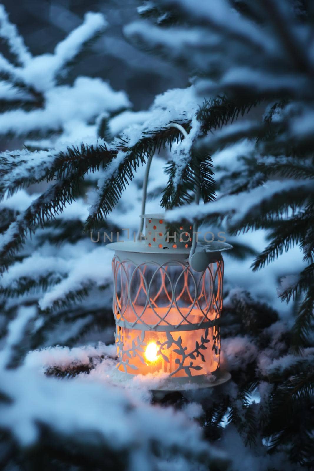Christmas lantern with burning candle on winter nature background.