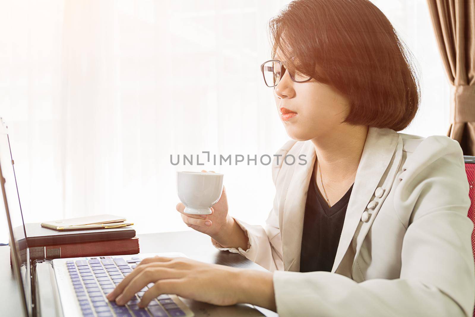 Woman teenage short hair in smart casual wear working on laptop while sit near window in home office