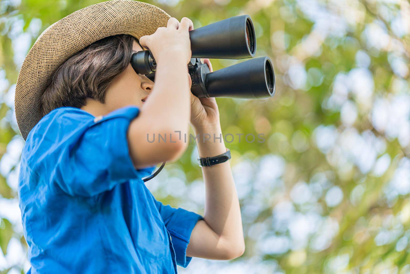 Close up Young asian woman short hair wear hat and hold binocular in grass field countryside Thailand